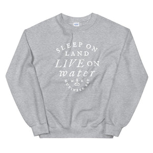 Light grey unisex sweatshirt with wording in white, "Sleep on Land, Live on Water" written in black artistic lettering on front. Underneath this is very small semi circle stating "Mutineer Bay" centered with small anchor. All lettering and images are in white.